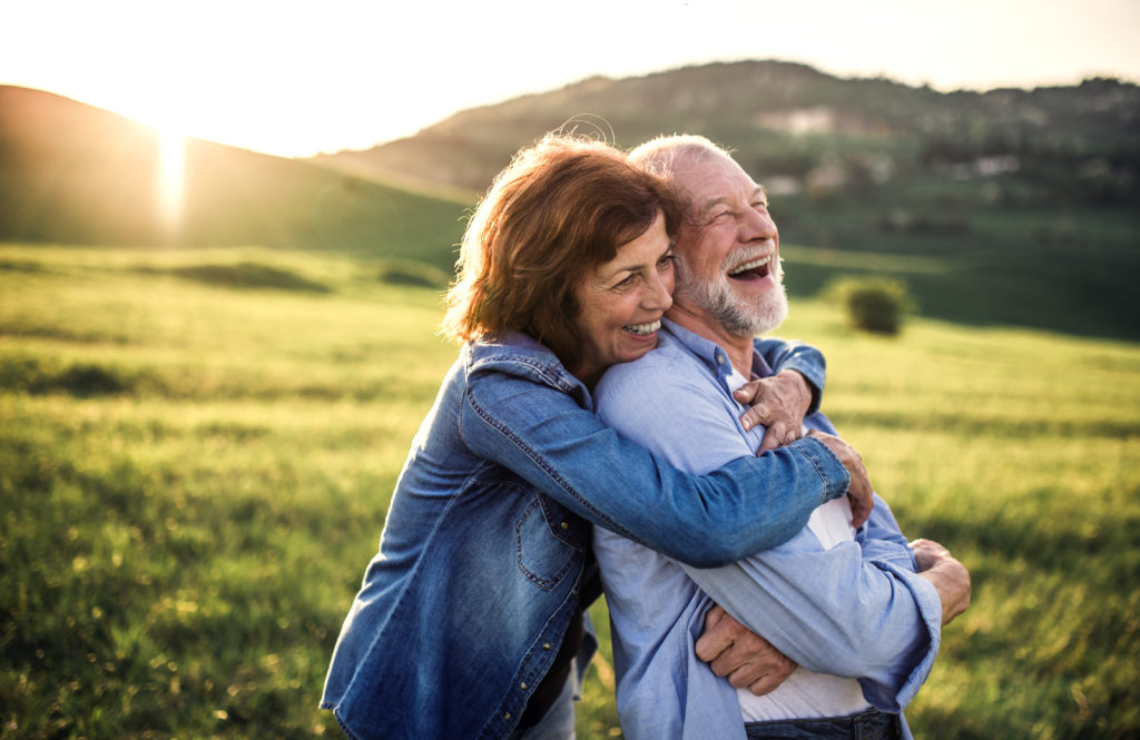 Elderly couple embracing in sunny meadow