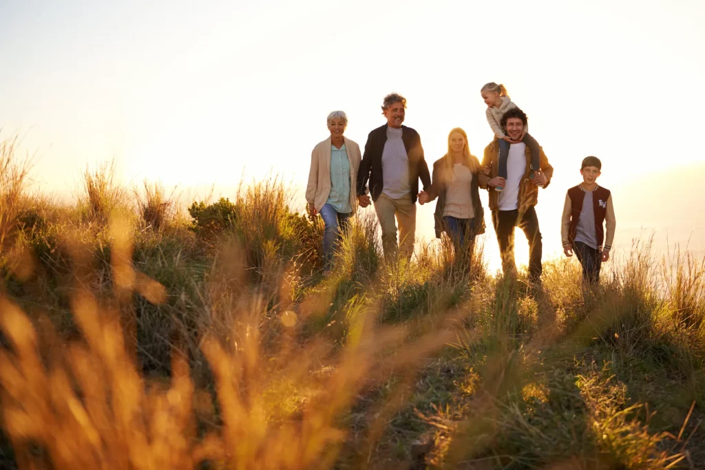 Family hiking at sunset in grassy field.