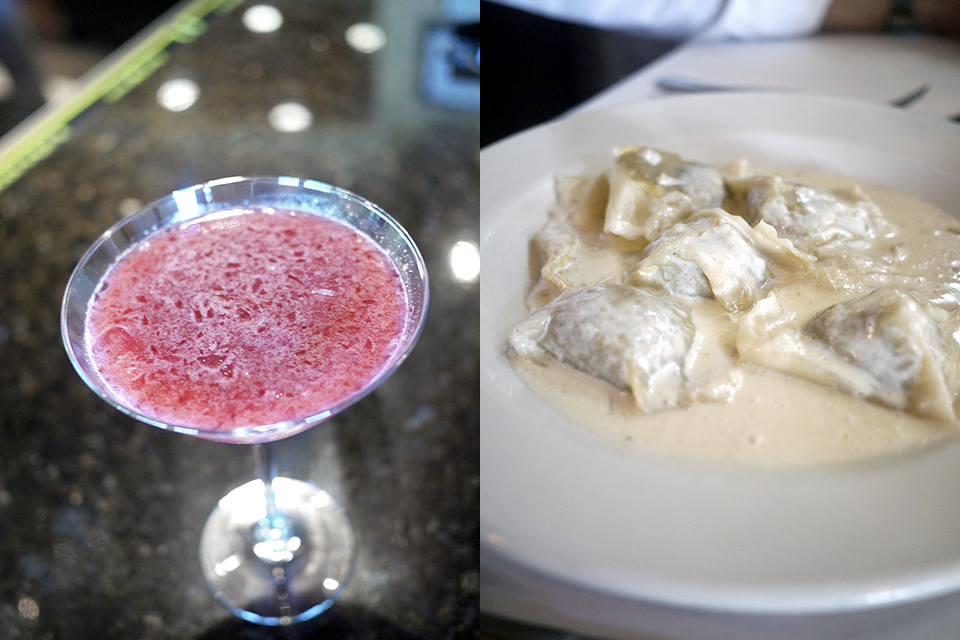 Frothy pink cocktail and creamy pasta dish on table.