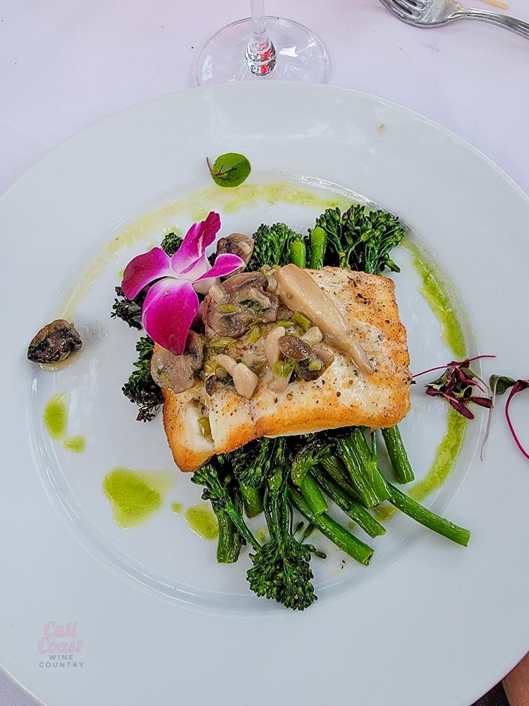 Grilled fish with vegetables and flower garnish.