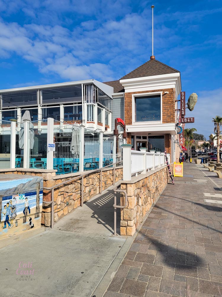 Seaside restaurant with outdoor seating and stone facade.