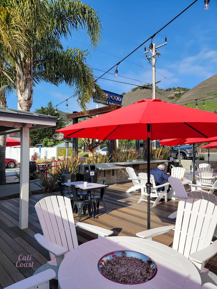 Outdoor patio with red umbrellas and Adirondack chairs.