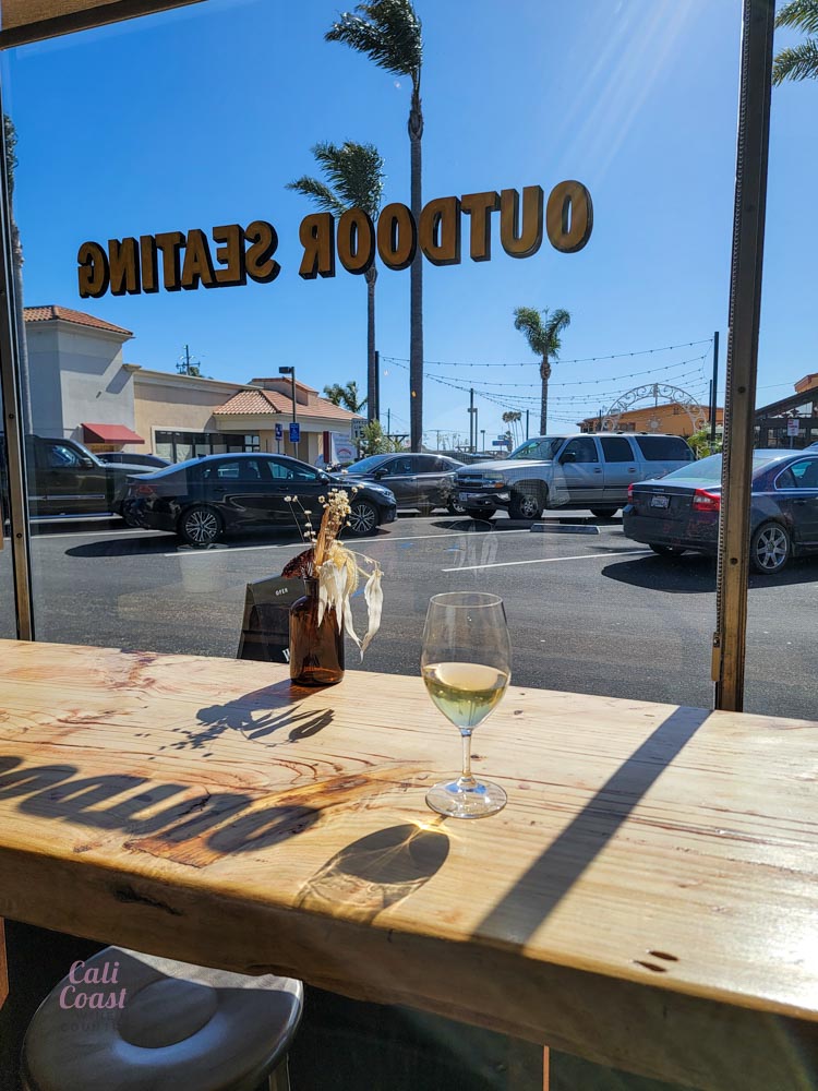 Wine glass on wooden table overlooking street view.